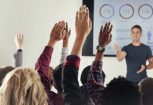 Cropped shot of a group of people raising their hands in a class